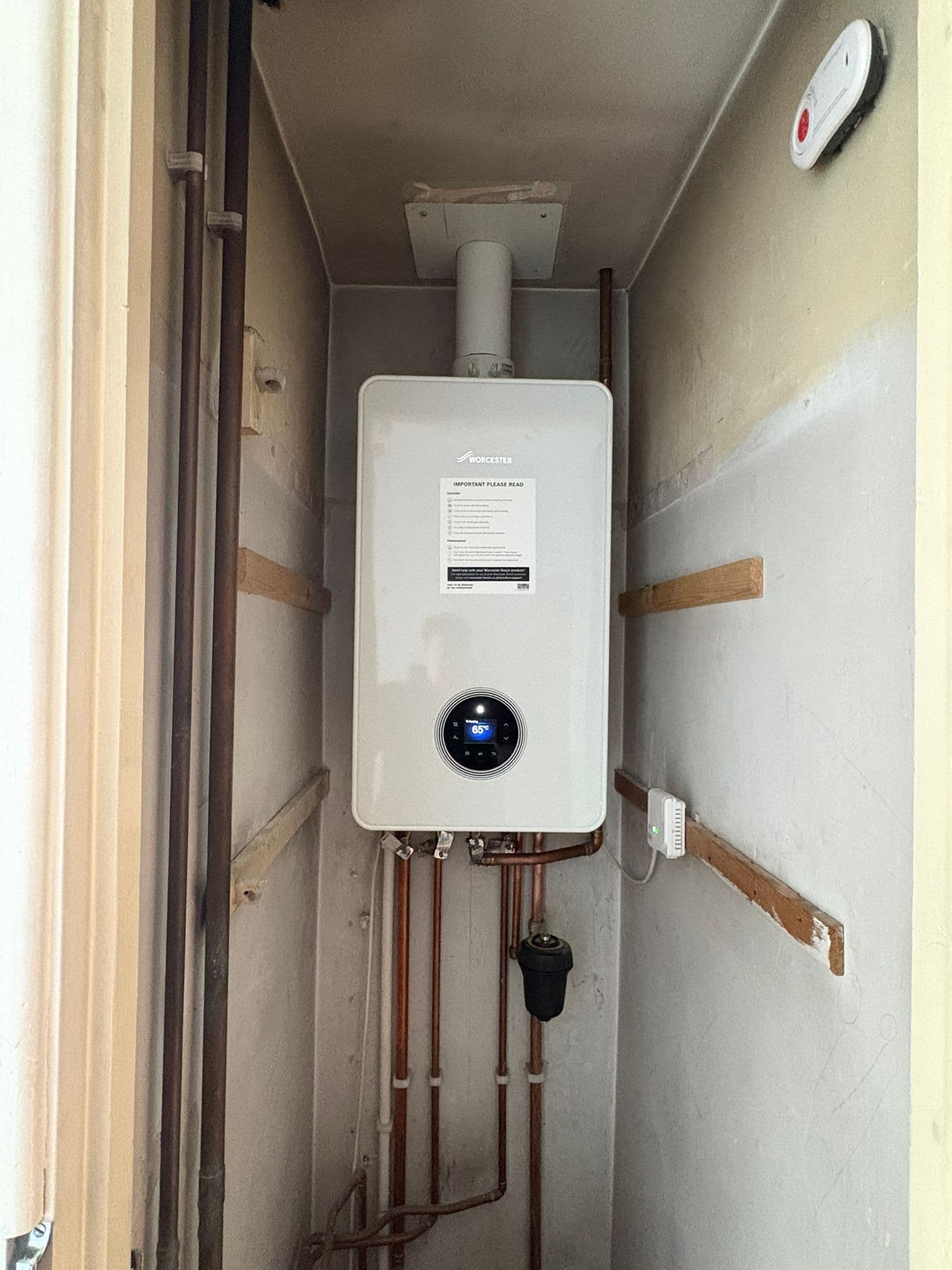 Worcester combi boiler fitted neatly into a tight stair recess with tidy pipework